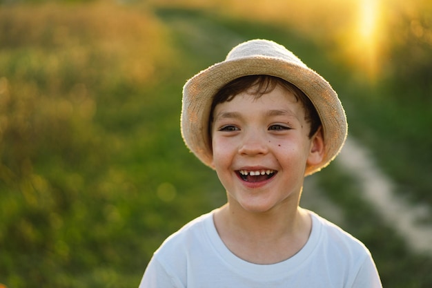 Portrait d'un petit garçon souriant dans un T-shirt blanc levant les mains et jouant