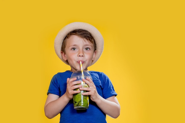 Portrait de petit garçon avec une tasse en plastique de limonade fraîche