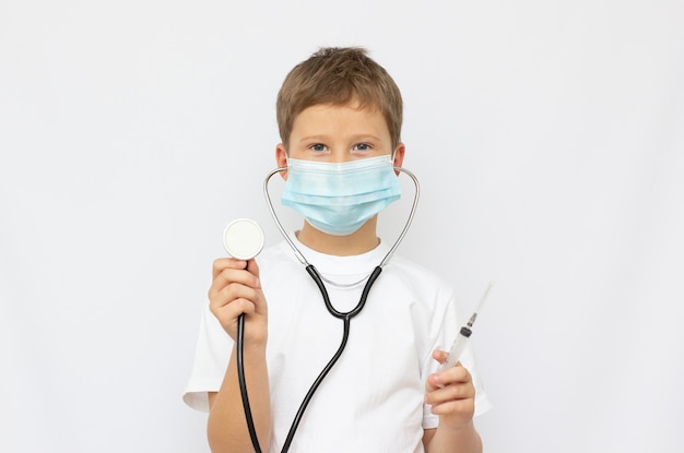 Portrait d'un petit médecin souriant avec stéthoscope et seringue. Isolé sur fond blanc