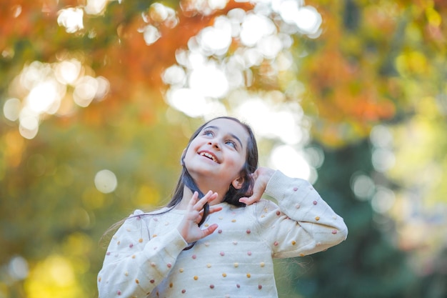 Portrait d'une petite belle fille de 9 ans avec de longs cheveux noirs dans des vêtements lumineux Enfant heureux dans le parc d'automne