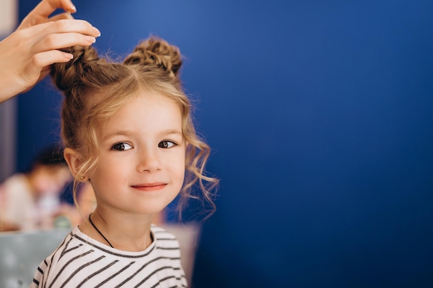 Portrait d'une petite belle fille avec une coiffure élégante dans un salon de beauté Le processus de fabrication des cheveux d'un enfant