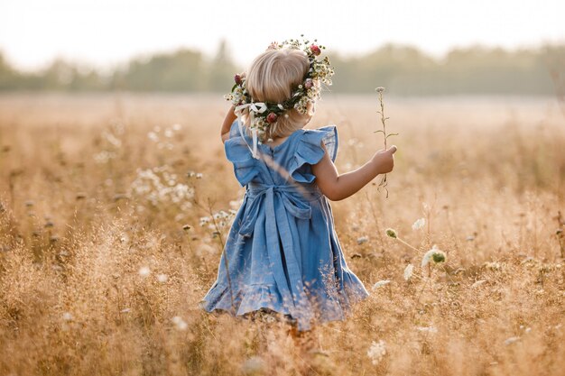 Photo portrait d'une petite belle fille en couronne florale sur la nature le jour de l'été