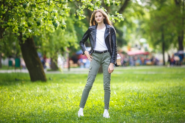 Portrait d'une petite belle fille élégante dans le parc de la ville sur fond de forêt verte