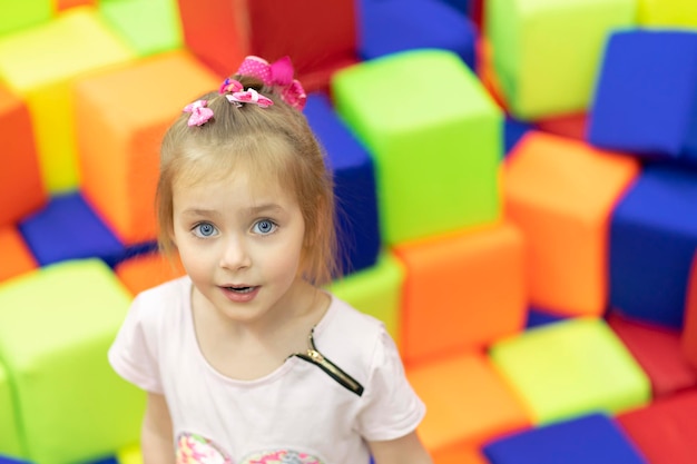 portrait d'une petite belle fille sur fond de cubes multicolores doux dans l'aire de jeux