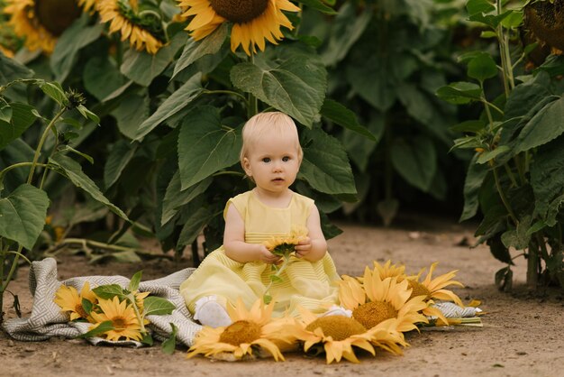 Portrait d'une petite belle fille heureuse d'un an avec un gâteau dans un champ de tournesols