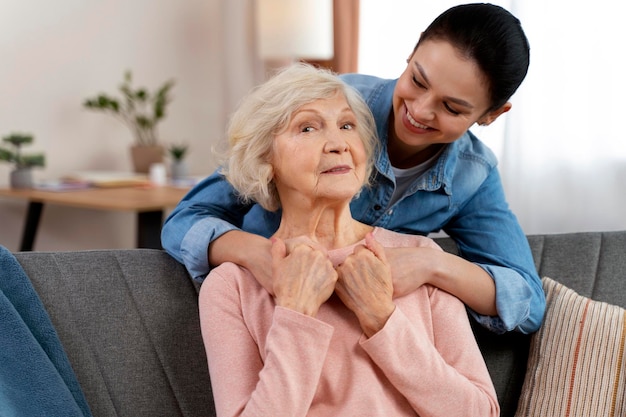 Portrait d'une petite-fille adulte heureuse et d'une grand-mère embrassant et souriant ensemble