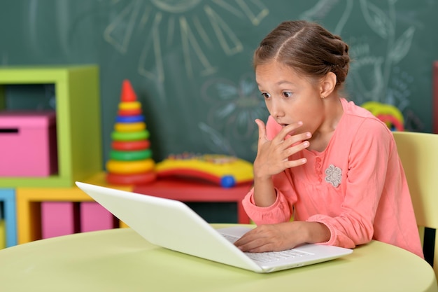 Portrait d'une petite fille à l'aide d'un ordinateur portable