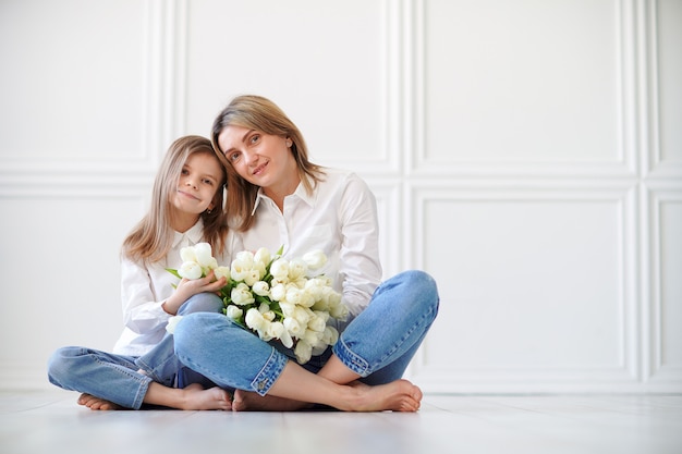 Portrait de petite fille aimante mère la tenant et les tulipes