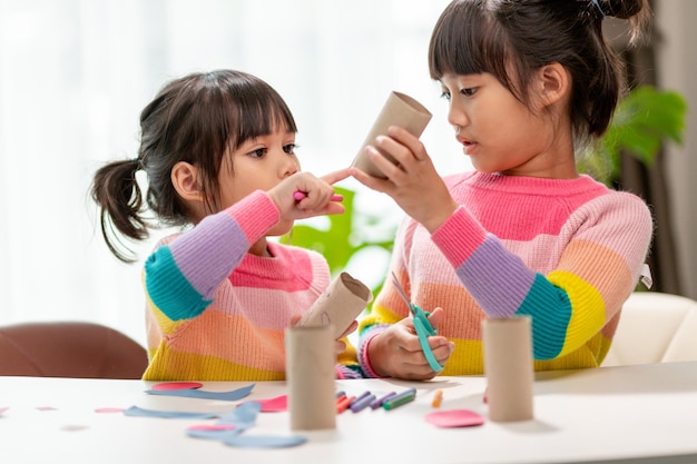 Portrait d'une petite fille asiatique coupant un papier lors d'activités sur le cours de bricolage à SchoolScissors papier découpé