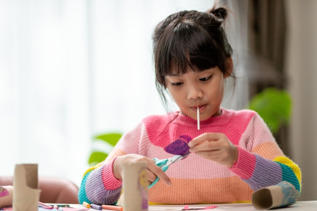 Portrait d'une petite fille asiatique coupant un papier lors d'activités sur le cours de bricolage à SchoolScissors papier découpé