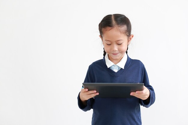 Portrait de petite fille asiatique enfant en uniforme scolaire à l'aide de tablet isolated on white