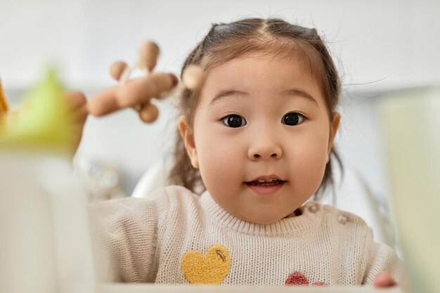 Portrait d'une petite fille asiatique regardant la caméra tout en jouant avec des jouets