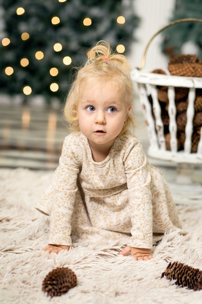 Portrait d'une petite fille aux cheveux blonds sur une photo d'un arbre de Noël et un décor du nouvel an à la veille de Noël