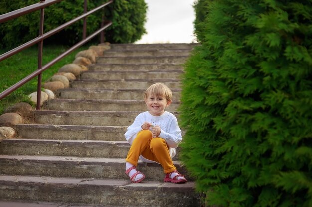 .Portrait d'une petite fille aux cheveux courts assise sur les escaliers dans le parc