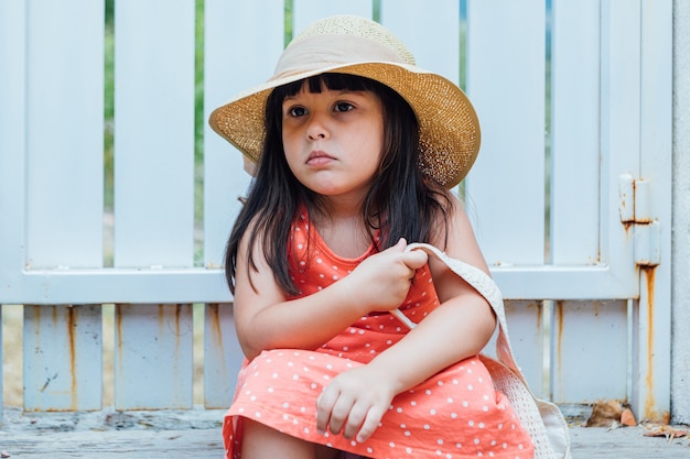 Portrait d'une petite fille aux cheveux noirs avec robe d'été, chapeau et sac