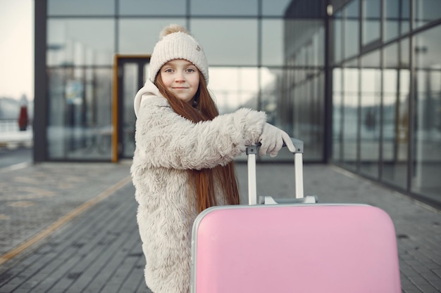 Portrait d'une petite fille avec des bagages allant au terminal de l'aéroport