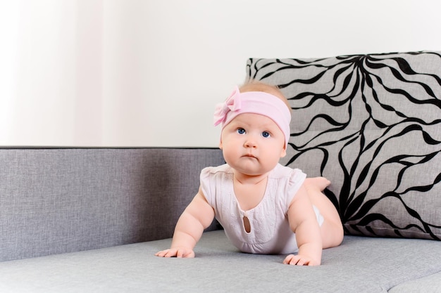 Portrait d'une petite fille avec un bandage et un arc sur la tête sur un canapé