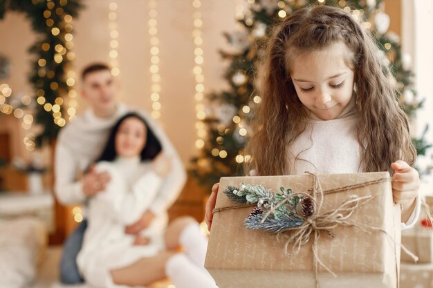 Portrait d'une petite fille avec boîte-cadeau et ses parents derrière