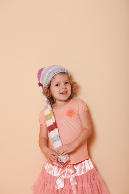 Portrait de petite fille bouclée dans le chapeau coloré d'hiver posant pour la photo