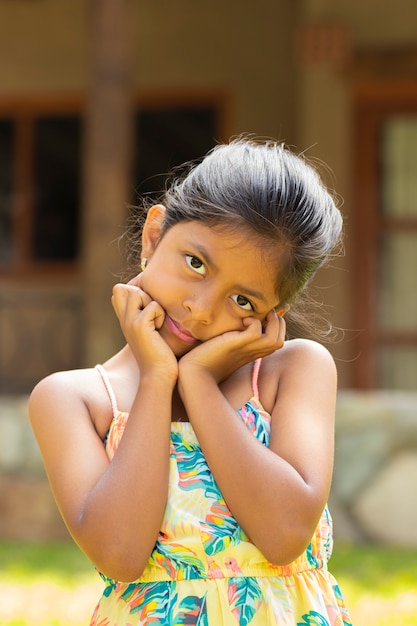 Portrait de petite fille brune avec ses mains sur son visage