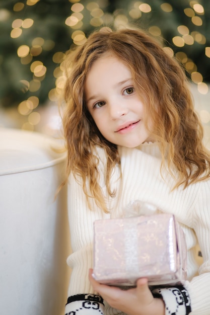 Portrait de petite fille cadeau d'ouverture devant l'arbre de Noël.