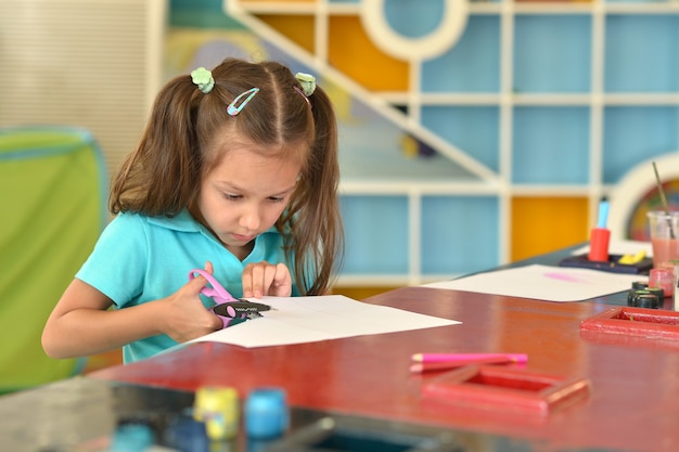 Le portrait d'une petite fille avec des ciseaux coupe le papier