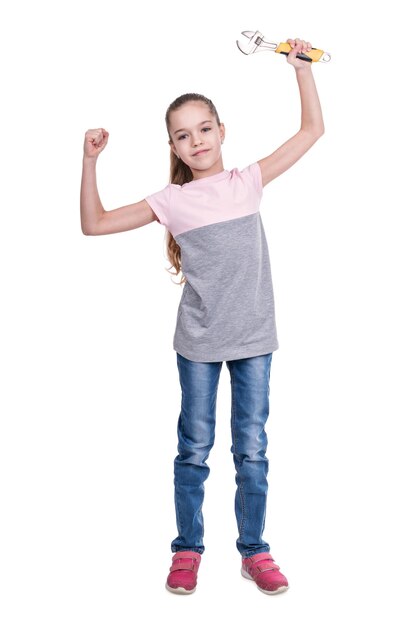 Portrait de petite fille avec une clé à molette à la main isolé sur fond blanc