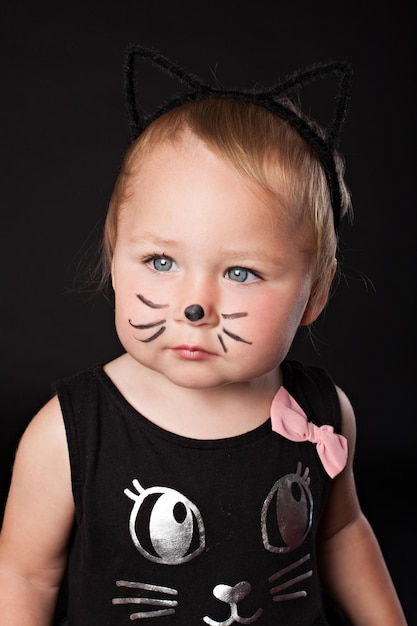 Portrait de petite fille en costume de chat sur fond noir