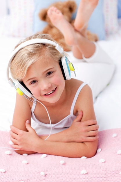 Portrait de petite fille couchée dans son lit en écoutant de la musique