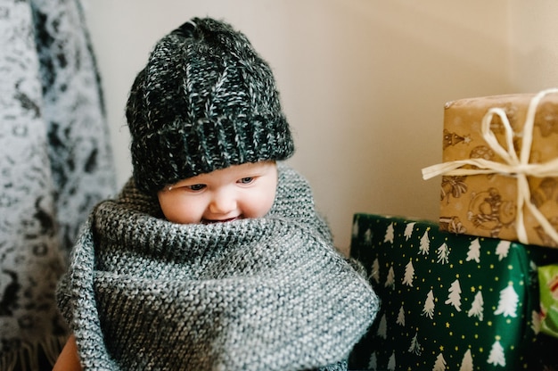 Portrait d'une petite fille dans un bonnet tricoté chaud avec un foulard se trouve dans la chambre