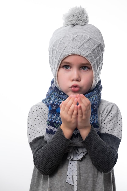 Portrait d'une petite fille dans un chapeau et une écharpe sur un fond blanc