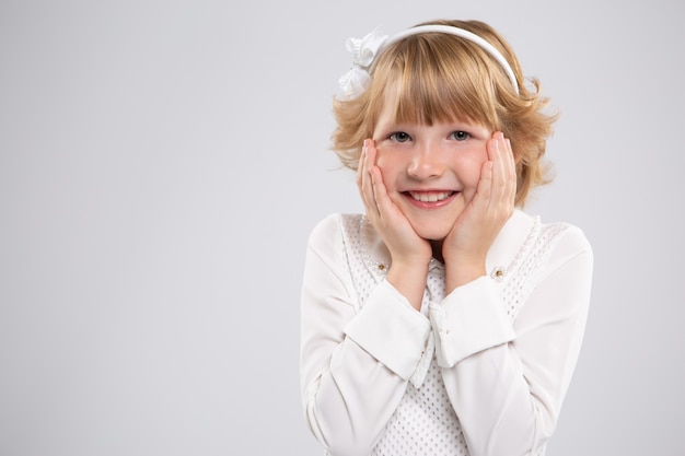 Portrait d'une petite fille, elle est heureuse et met ses mains sur ses joues. Émotion vive.