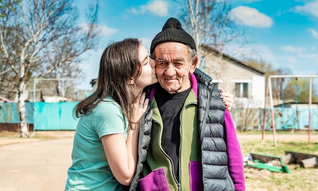 Photo portrait d'une petite-fille embrassant sur la joue son grand-père de 75 ans dans un village russe