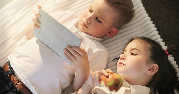 Portrait de petite fille et garçon à l'aide de tablette numérique