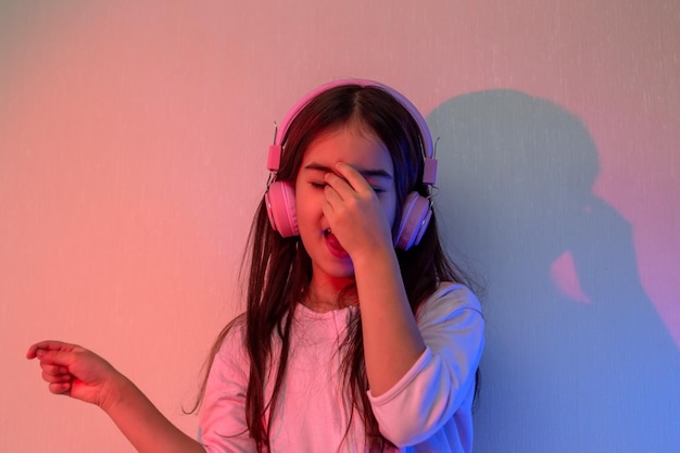 Portrait d'une petite fille heureuse dansante dans des écouteurs roses