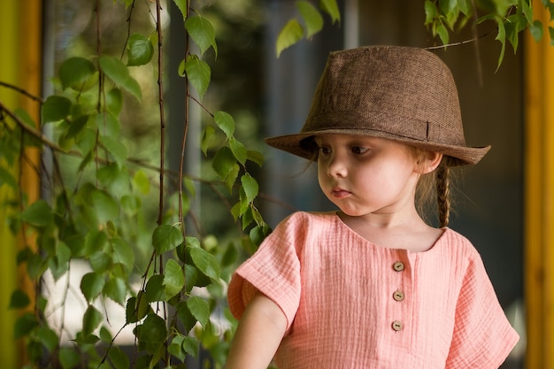 Portrait d'une petite fille heureuse et mignonne dans un chapeau marron de style rural et des vêtements de mousseline dans une journée d'été.