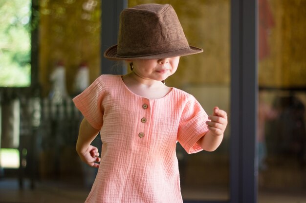 Portrait d'une petite fille heureuse et mignonne dans un chapeau marron de style rural et des vêtements de mousseline dans une journée d'été.