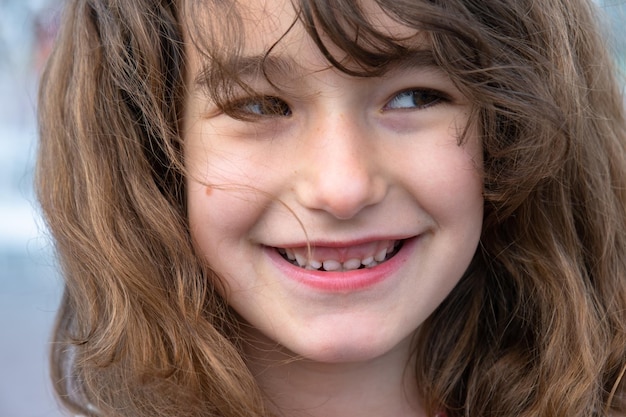 Portrait d'une petite fille heureuse avec un sourire vif et malicieux en gros plan avec des cheveux courts et bouclés