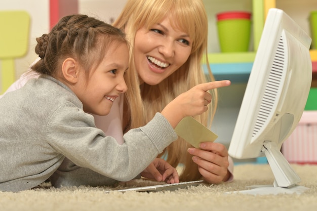 Portrait d'une petite fille jouant avec sa mère sur ordinateur à la maison