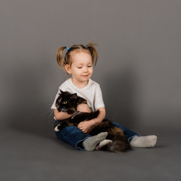 Portrait d'une petite fille jouant avec son animal de compagnie, gros chat noir