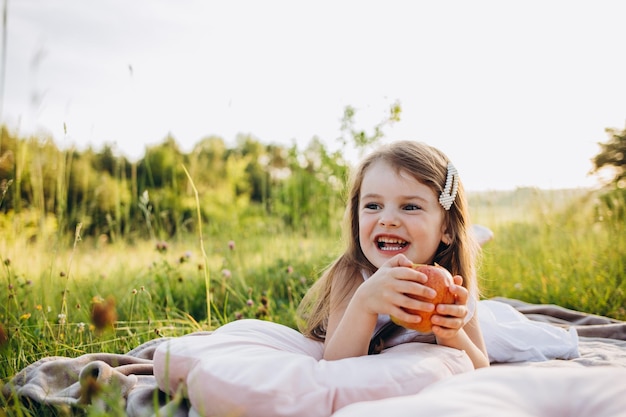 Portrait de petite fille mangeant une pomme rouge en plein air