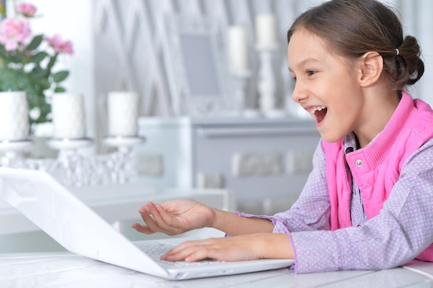 Portrait de petite fille mignonne à l'aide d'un ordinateur portable moderne