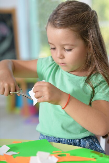 Le portrait de la petite fille mignonne coupe le papier de couleur