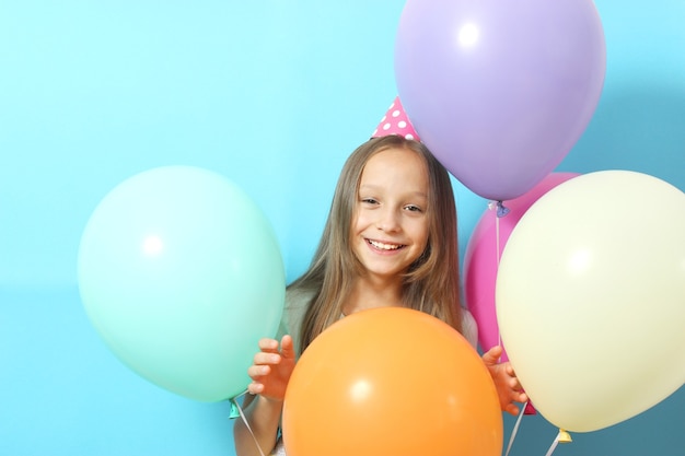 Portrait d'une petite fille mignonne dans un chapeau de fête et avec des ballons