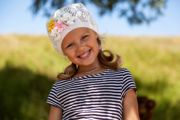Un portrait d'une petite fille mignonne qui rit et rit joyeusement dans le parc par une chaude journée d'été. Concept de vacances d'été en mer et style de vie