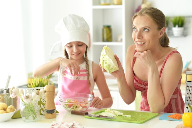 Portrait d'une petite fille mignonne avec sa mère cuisinant ensemble à la table de la cuisine