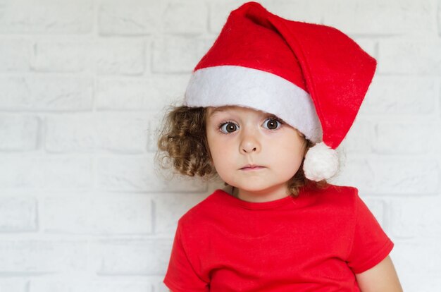 Portrait de petite fille mignonne surprise en costume rouge et bonnet de Noel pour Noël