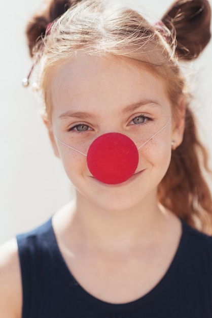 Portrait d'une petite fille avec un nez de clown dans la rue