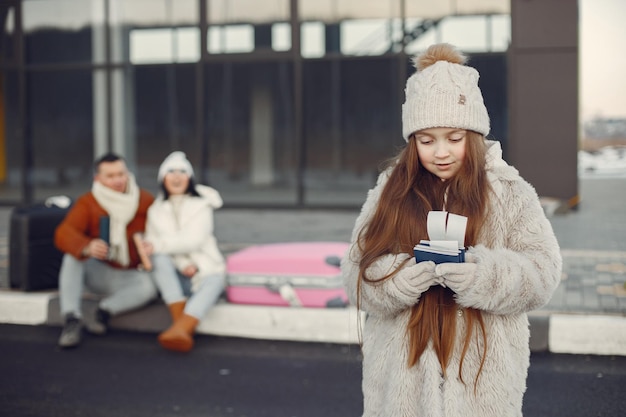 Portrait d'une petite fille avec des passeports et ses parents derrière