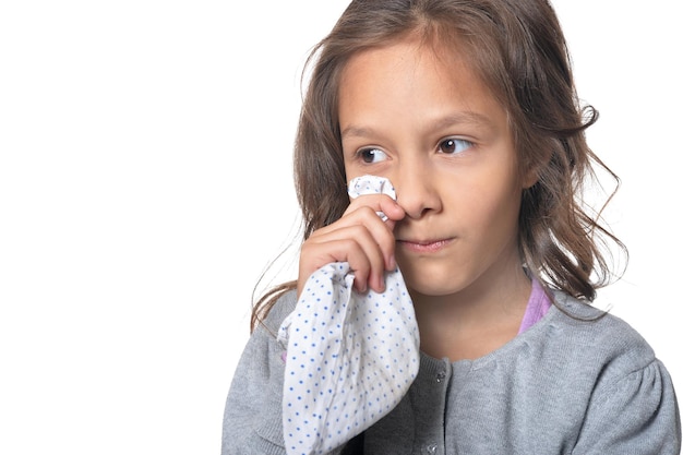 Portrait d'une petite fille pleurant, posant contre le blanc